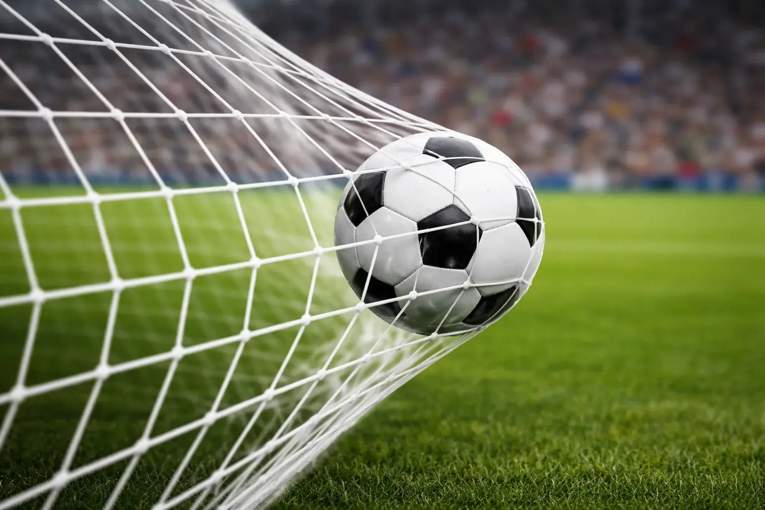 Voetbal in het net bij een doelpunt met scorebord op de achtergrond